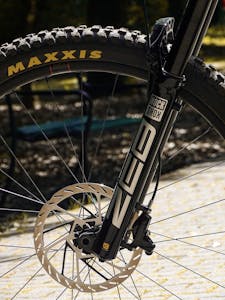 Detailed view of a mountain bike's front wheel featuring a Maxxis tire and disc brake system.